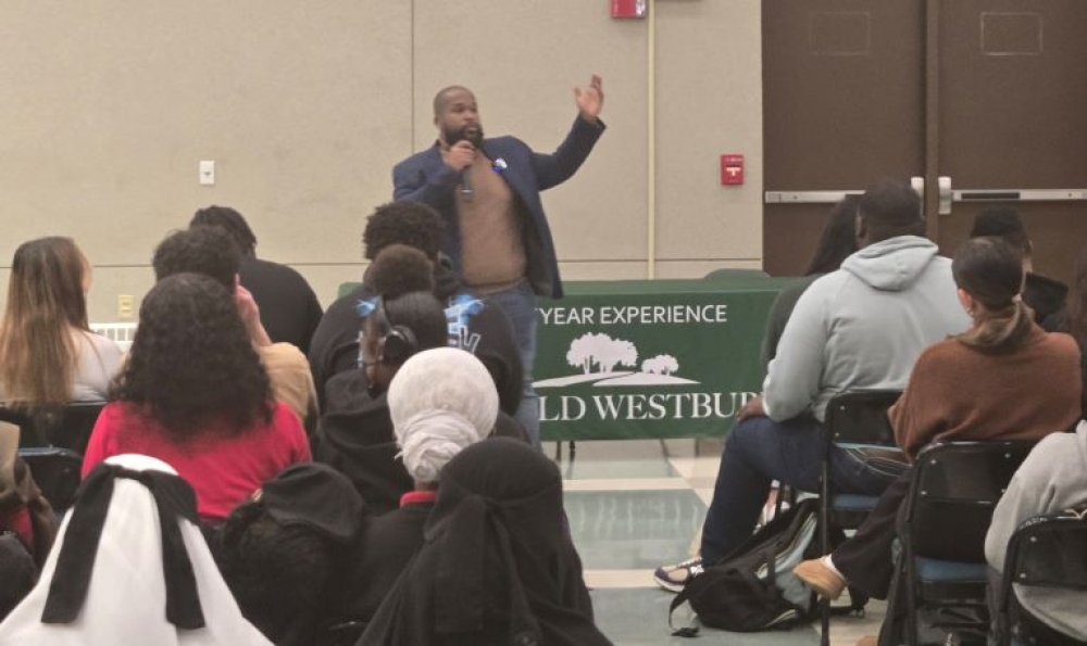 African American man stands and speaks before an audience of young people