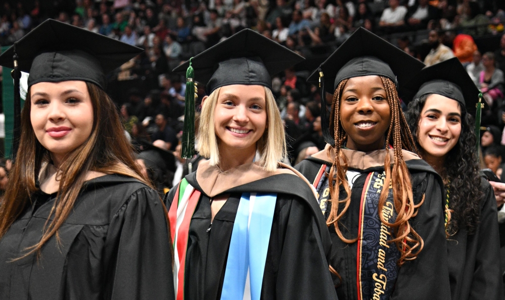 Four smiling female graduates dressed in regalia
