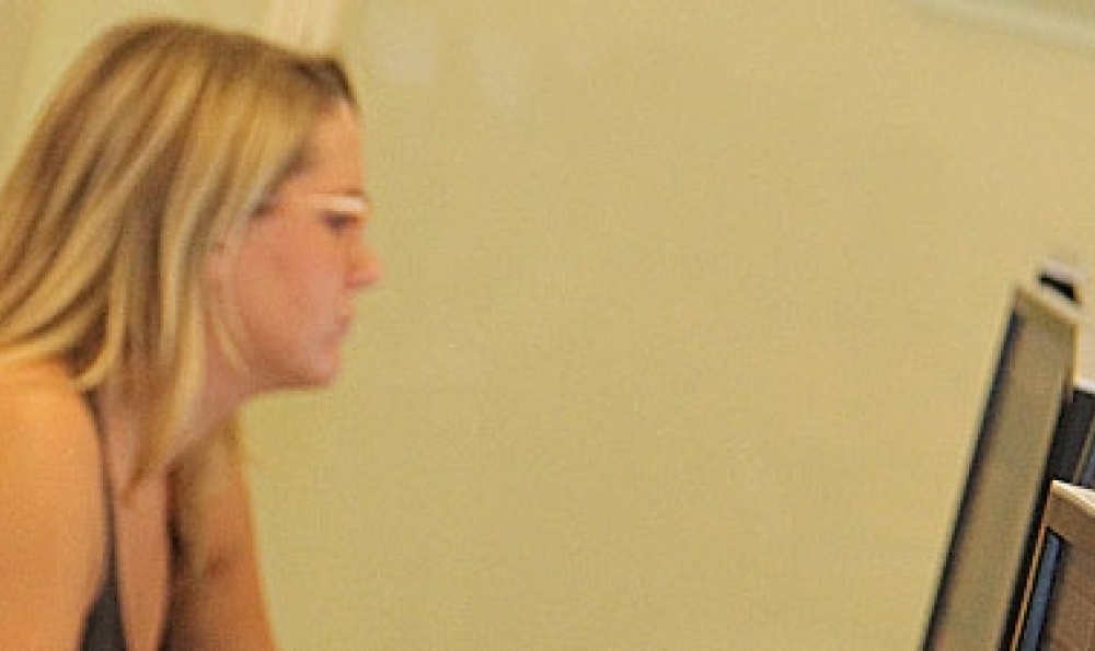 Three students in a classroom looking at a monitor