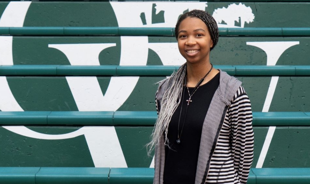 Young African American woman with long braided hair standing in front of a staircase with the letters O and W painted on them