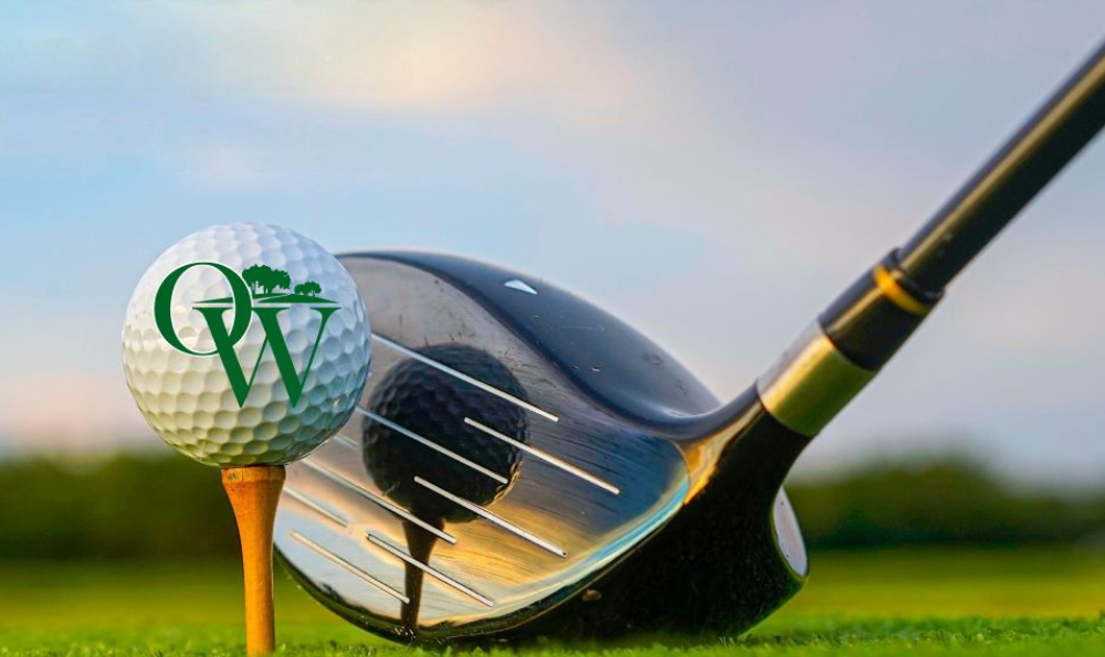 Golf ball with OW brand mark on a tee with a driver positioned behind it